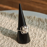 This adjustable S925 sterling silver ring features a striking baroque pearl at its center, set within an organic, flowing silver frame that wraps around the irregular, lustrous gemstone. The open, sculptural metalwork creates a modern, artistic silhouette, showcasing the pearl's natural, one-of-a-kind texture and soft iridescence. The sleek, polished silver band complements the unique pearl, making it a standout piece with a contemporary, bohemian aesthetic.
