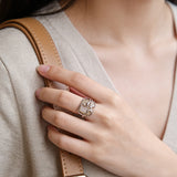 This adjustable S925 sterling silver ring features a striking baroque pearl at its center, set within an organic, flowing silver frame that wraps around the irregular, lustrous gemstone. The open, sculptural metalwork creates a modern, artistic silhouette, showcasing the pearl's natural, one-of-a-kind texture and soft iridescence. The sleek, polished silver band complements the unique pearl, making it a standout piece with a contemporary, bohemian aesthetic.