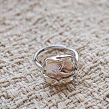 This adjustable S925 sterling silver ring features a striking baroque pearl at its center, set within an organic, flowing silver frame that wraps around the irregular, lustrous gemstone. The open, sculptural metalwork creates a modern, artistic silhouette, showcasing the pearl's natural, one-of-a-kind texture and soft iridescence. The sleek, polished silver band complements the unique pearl, making it a standout piece with a contemporary, bohemian aesthetic.
