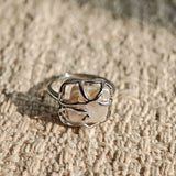 This adjustable S925 sterling silver ring features a striking baroque pearl at its center, set within an organic, flowing silver frame that wraps around the irregular, lustrous gemstone. The open, sculptural metalwork creates a modern, artistic silhouette, showcasing the pearl's natural, one-of-a-kind texture and soft iridescence. The sleek, polished silver band complements the unique pearl, making it a standout piece with a contemporary, bohemian aesthetic.