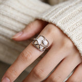 This adjustable S925 sterling silver ring features a striking baroque pearl at its center, set within an organic, flowing silver frame that wraps around the irregular, lustrous gemstone. The open, sculptural metalwork creates a modern, artistic silhouette, showcasing the pearl's natural, one-of-a-kind texture and soft iridescence. The sleek, polished silver band complements the unique pearl, making it a standout piece with a contemporary, bohemian aesthetic.