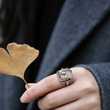 This adjustable S925 sterling silver ring features a striking baroque pearl at its center, set within an organic, flowing silver frame that wraps around the irregular, lustrous gemstone. The open, sculptural metalwork creates a modern, artistic silhouette, showcasing the pearl's natural, one-of-a-kind texture and soft iridescence. The sleek, polished silver band complements the unique pearl, making it a standout piece with a contemporary, bohemian aesthetic.