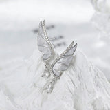 These S925 sterling silver earrings are designed in the shape of delicate butterfly wings, with a resin craft on the wing surfaces and a row of shimmering cubic zirconia along the edges. A teardrop-cut clear gemstone dangles elegantly from the bottom of each wing, adding a graceful and sparkling touch to the overall design.