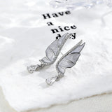 These S925 sterling silver earrings are designed in the shape of delicate butterfly wings, with a resin craft on the wing surfaces and a row of shimmering cubic zirconia along the edges. A teardrop-cut clear gemstone dangles elegantly from the bottom of each wing, adding a graceful and sparkling touch to the overall design.