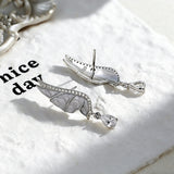These S925 sterling silver earrings are designed in the shape of delicate butterfly wings, with a resin craft on the wing surfaces and a row of shimmering cubic zirconia along the edges. A teardrop-cut clear gemstone dangles elegantly from the bottom of each wing, adding a graceful and sparkling touch to the overall design.