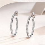 These 925 sterling silver hoop earrings are elegantly lined with sparkling moissanite stones along their entire length, creating a continuous, luminous sheen. The sleek, open-hoop design is secured with a classic butterfly back, blending timeless elegance with modern sophistication. The polished silver finish enhances the brilliance of the moissanite, making them a versatile accessory for both everyday wear and special occasions.
