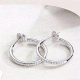 These 925 sterling silver hoop earrings are elegantly lined with sparkling moissanite stones along their entire length, creating a continuous, luminous sheen. The sleek, open-hoop design is secured with a classic butterfly back, blending timeless elegance with modern sophistication. The polished silver finish enhances the brilliance of the moissanite, making them a versatile accessory for both everyday wear and special occasions.