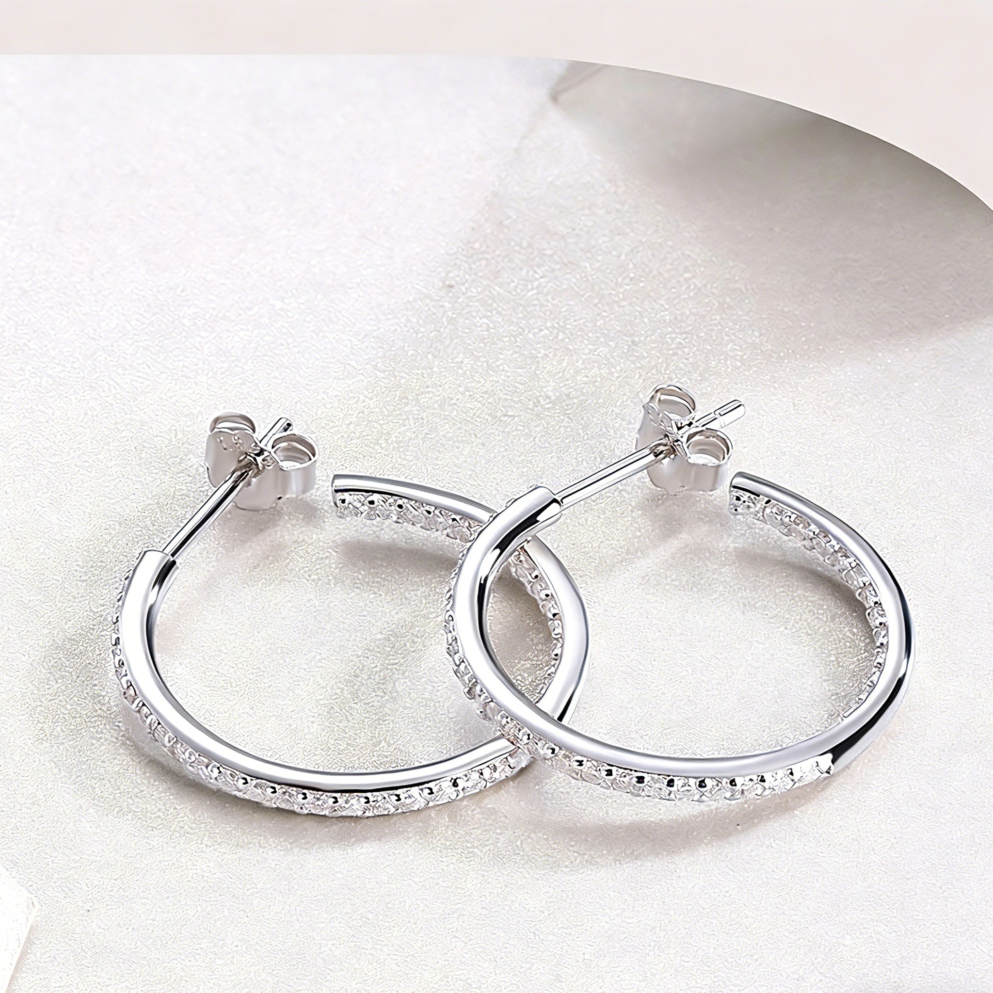 These 925 sterling silver hoop earrings are elegantly lined with sparkling moissanite stones along their entire length, creating a continuous, luminous sheen. The sleek, open-hoop design is secured with a classic butterfly back, blending timeless elegance with modern sophistication. The polished silver finish enhances the brilliance of the moissanite, making them a versatile accessory for both everyday wear and special occasions.