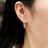 These 925 sterling silver hoop earrings are elegantly lined with sparkling moissanite stones along their entire length, creating a continuous, luminous sheen. The sleek, open-hoop design is secured with a classic butterfly back, blending timeless elegance with modern sophistication. The polished silver finish enhances the brilliance of the moissanite, making them a versatile accessory for both everyday wear and special occasions.