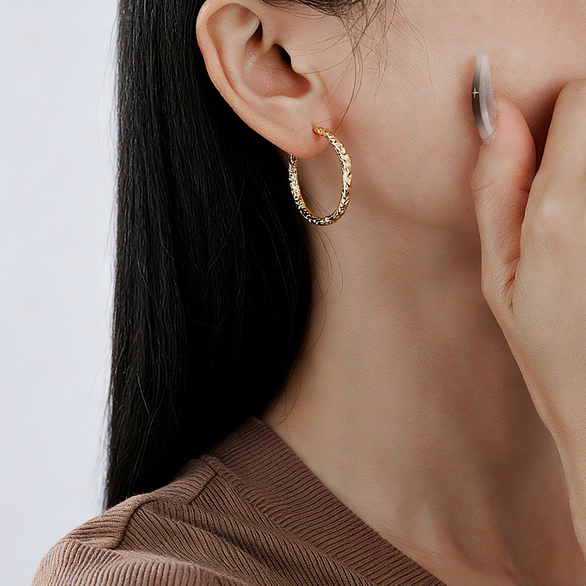 These S925 sterling silver hoop earrings feature a textured, molten lava-like finish in a warm gold tone. The organic, uneven surface creates a rugged, handcrafted appearance, while the classic oval hoop shape adds a timeless, elegant touch to the design. The secure post-back closure ensures comfortable all-day wear.