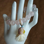 Delicate rose tones mingle with rare azure streaks, then an amber star, adjustable agate bead, and soft tassel complete the story.
