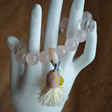 Delicate rose tones mingle with rare azure streaks, then an amber star, adjustable agate bead, and soft tassel complete the story.
