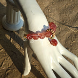 This bracelet features a beautiful blend of translucent white phantom quartz beads and rich pink strawberry quartz beads, creating a striking contrast. Adorned with delicate gold-toned accents and a charming red cat's paw charm, it exudes a sweet and elegant vibe. The combination of smooth crystal spheres and a playful pendant makes it a lovely and eye-catching accessory.