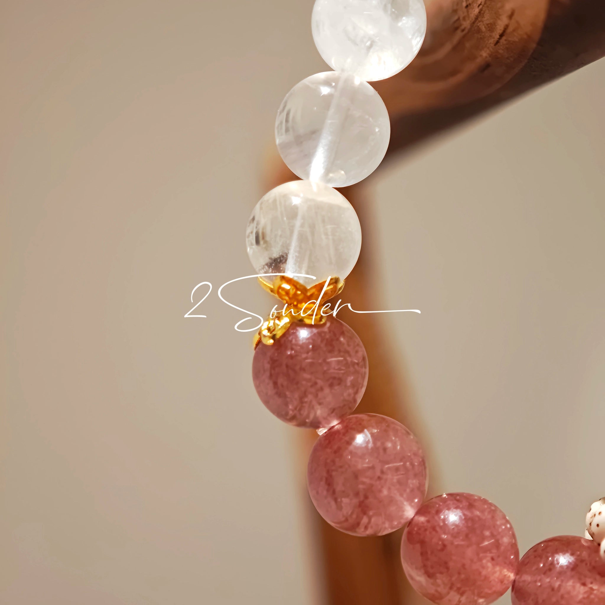 This bracelet features a beautiful blend of translucent white phantom quartz beads and rich pink strawberry quartz beads, creating a striking contrast. Adorned with delicate gold-toned accents and a charming red cat's paw charm, it exudes a sweet and elegant vibe. The combination of smooth crystal spheres and a playful pendant makes it a lovely and eye-catching accessory.
