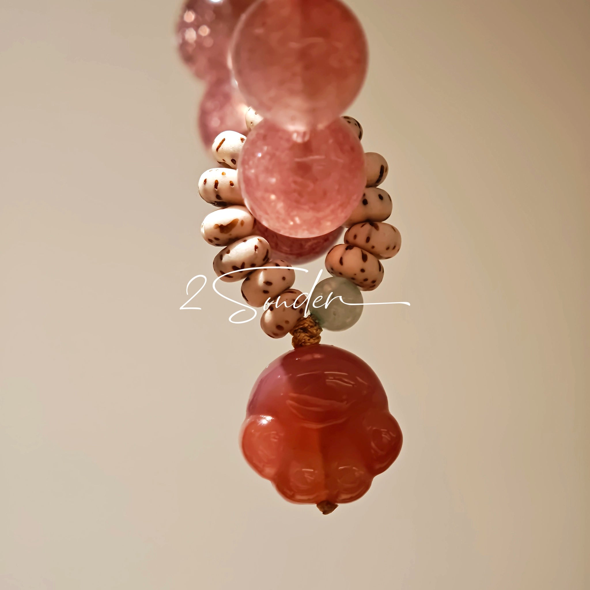 This bracelet features a beautiful blend of translucent white phantom quartz beads and rich pink strawberry quartz beads, creating a striking contrast. Adorned with delicate gold-toned accents and a charming red cat's paw charm, it exudes a sweet and elegant vibe. The combination of smooth crystal spheres and a playful pendant makes it a lovely and eye-catching accessory.
