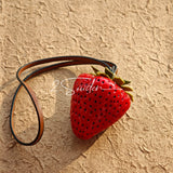 This is a simulated strawberry bag charm. The charm features a strawberry, the same size as a real strawberry, and is made of high-quality resin, giving it a very realistic appearance. It also has a leather cord attached, allowing it to be hung on bags, earphone cases, or used as a keychain. It's versatile and very cute.