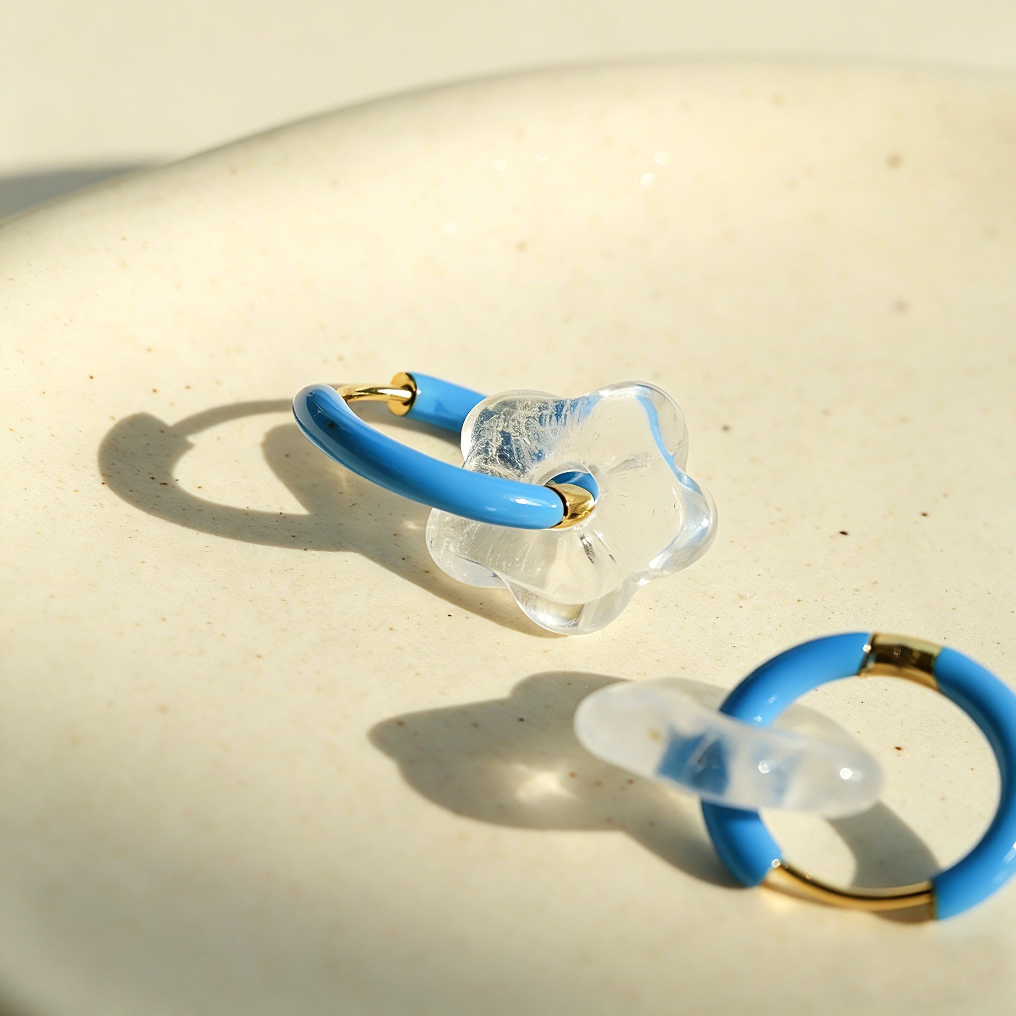 These summer candy-colored hoop earrings feature cute carved natural stone flower pendants paired with glossy enamel-coated metal hoops. They come in a vibrant palette of playful bright hues, creating a fresh, sweet and youthful summery style. The minimalist huggie hoop structure with delicate floral charms makes them lightweight and versatile for daily casual wear.