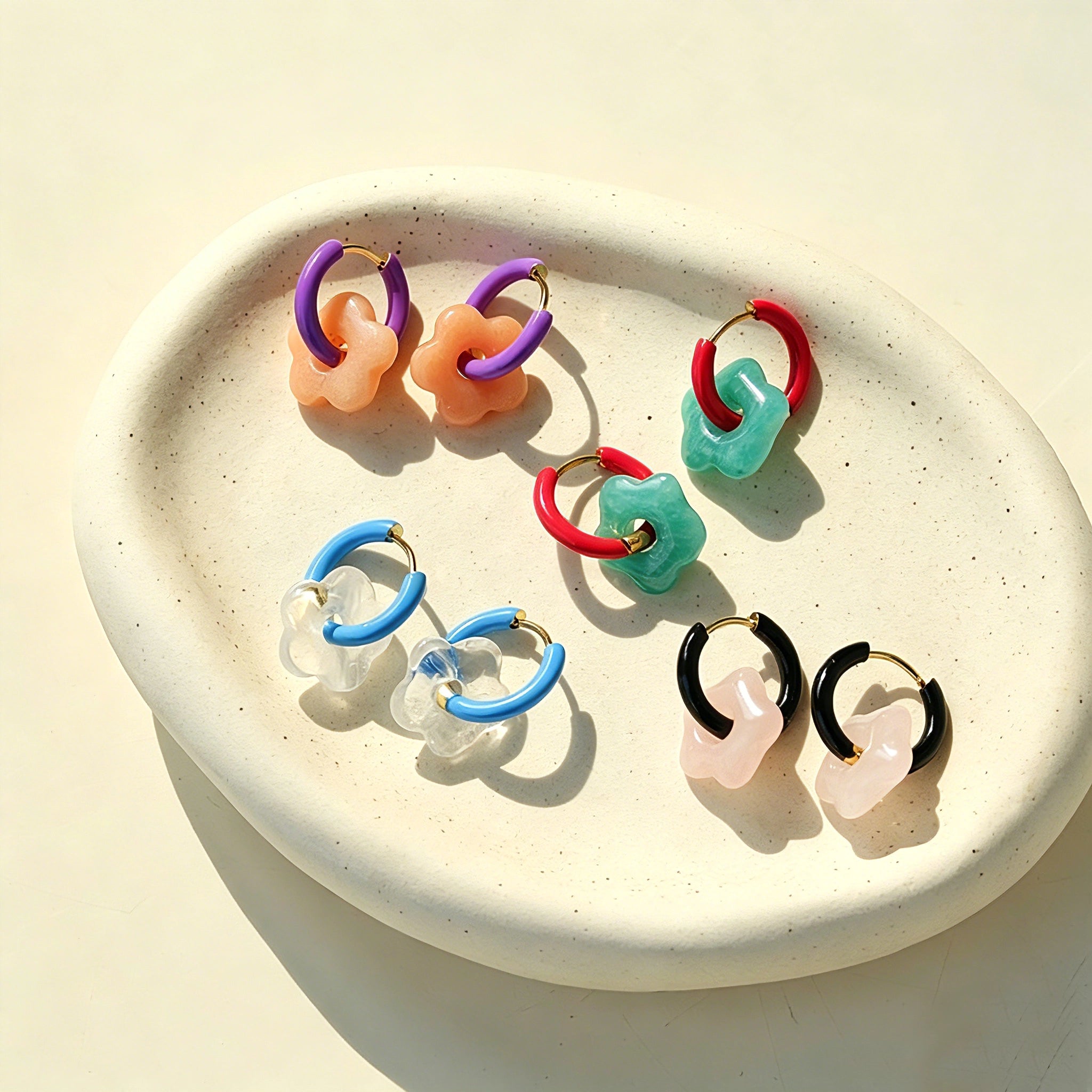 These summer candy-colored hoop earrings feature cute carved natural stone flower pendants paired with glossy enamel-coated metal hoops. They come in a vibrant palette of playful bright hues, creating a fresh, sweet and youthful summery style. The minimalist huggie hoop structure with delicate floral charms makes them lightweight and versatile for daily casual wear.