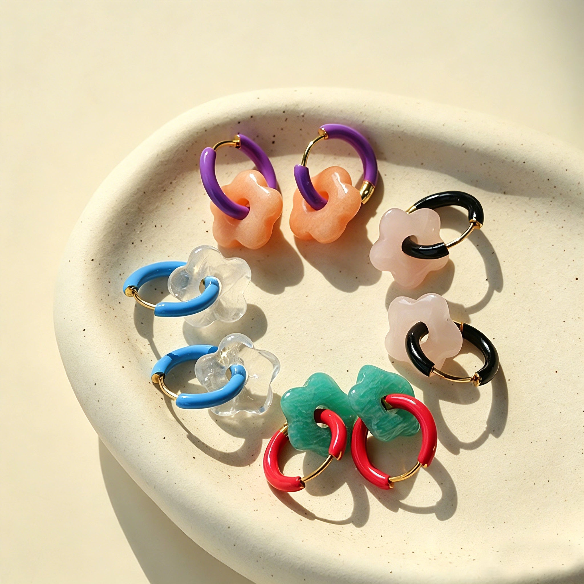 These summer candy-colored hoop earrings feature cute carved natural stone flower pendants paired with glossy enamel-coated metal hoops. They come in a vibrant palette of playful bright hues, creating a fresh, sweet and youthful summery style. The minimalist huggie hoop structure with delicate floral charms makes them lightweight and versatile for daily casual wear.