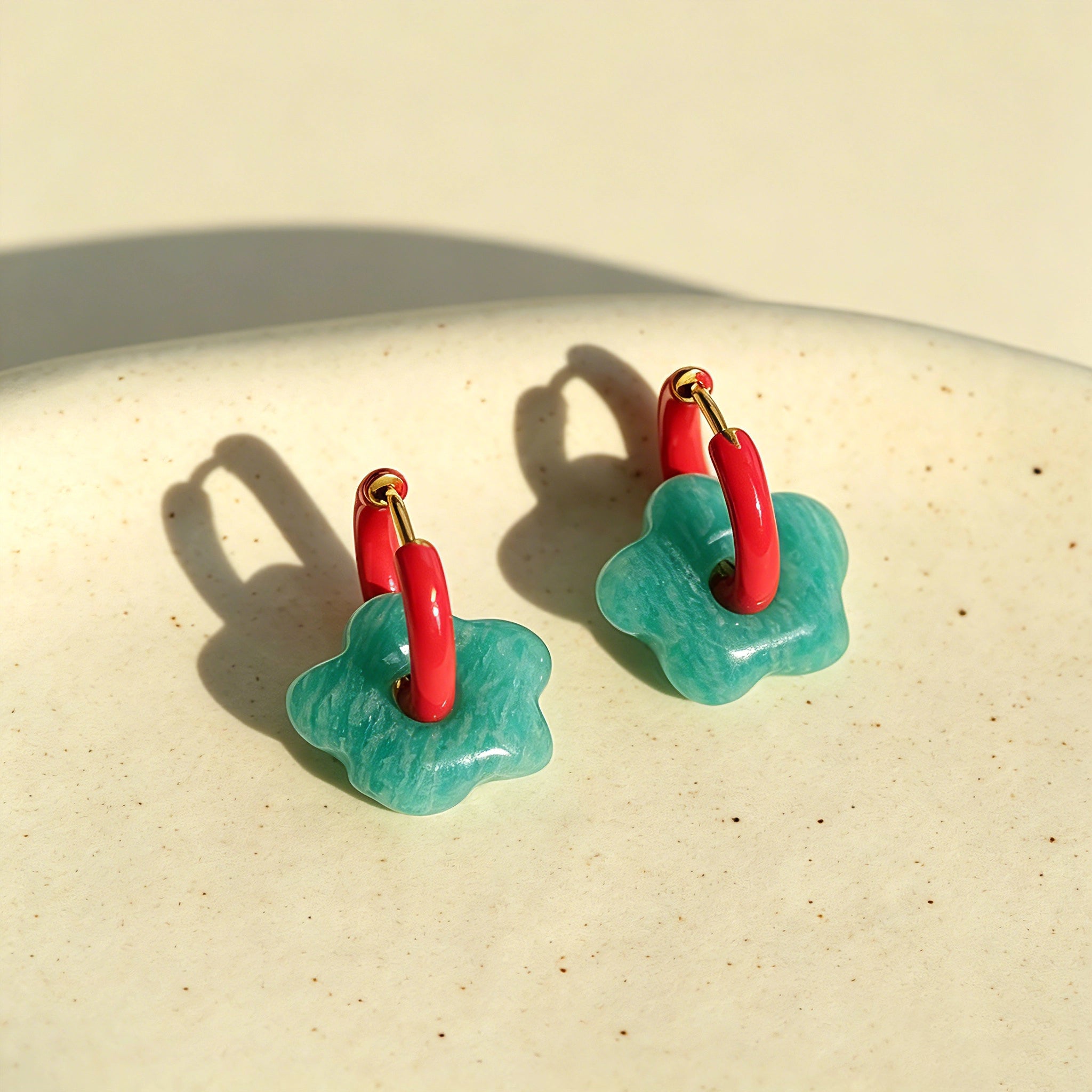 These summer candy-colored hoop earrings feature cute carved natural stone flower pendants paired with glossy enamel-coated metal hoops. They come in a vibrant palette of playful bright hues, creating a fresh, sweet and youthful summery style. The minimalist huggie hoop structure with delicate floral charms makes them lightweight and versatile for daily casual wear.