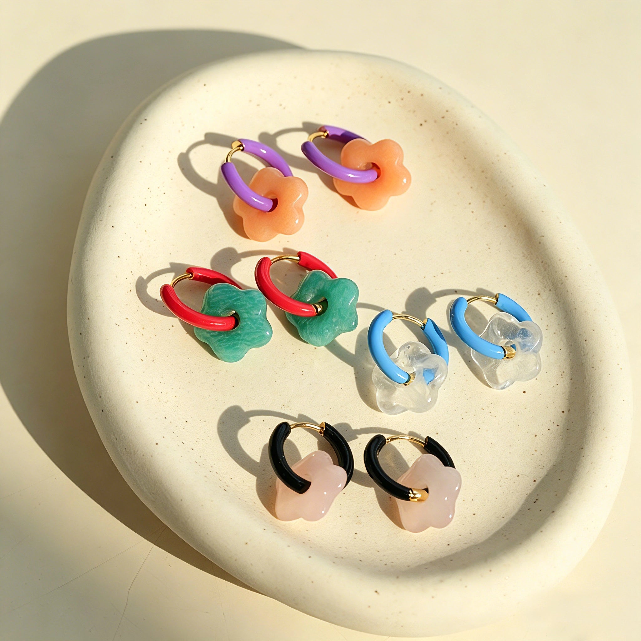 These summer candy-colored hoop earrings feature cute carved natural stone flower pendants paired with glossy enamel-coated metal hoops. They come in a vibrant palette of playful bright hues, creating a fresh, sweet and youthful summery style. The minimalist huggie hoop structure with delicate floral charms makes them lightweight and versatile for daily casual wear.
