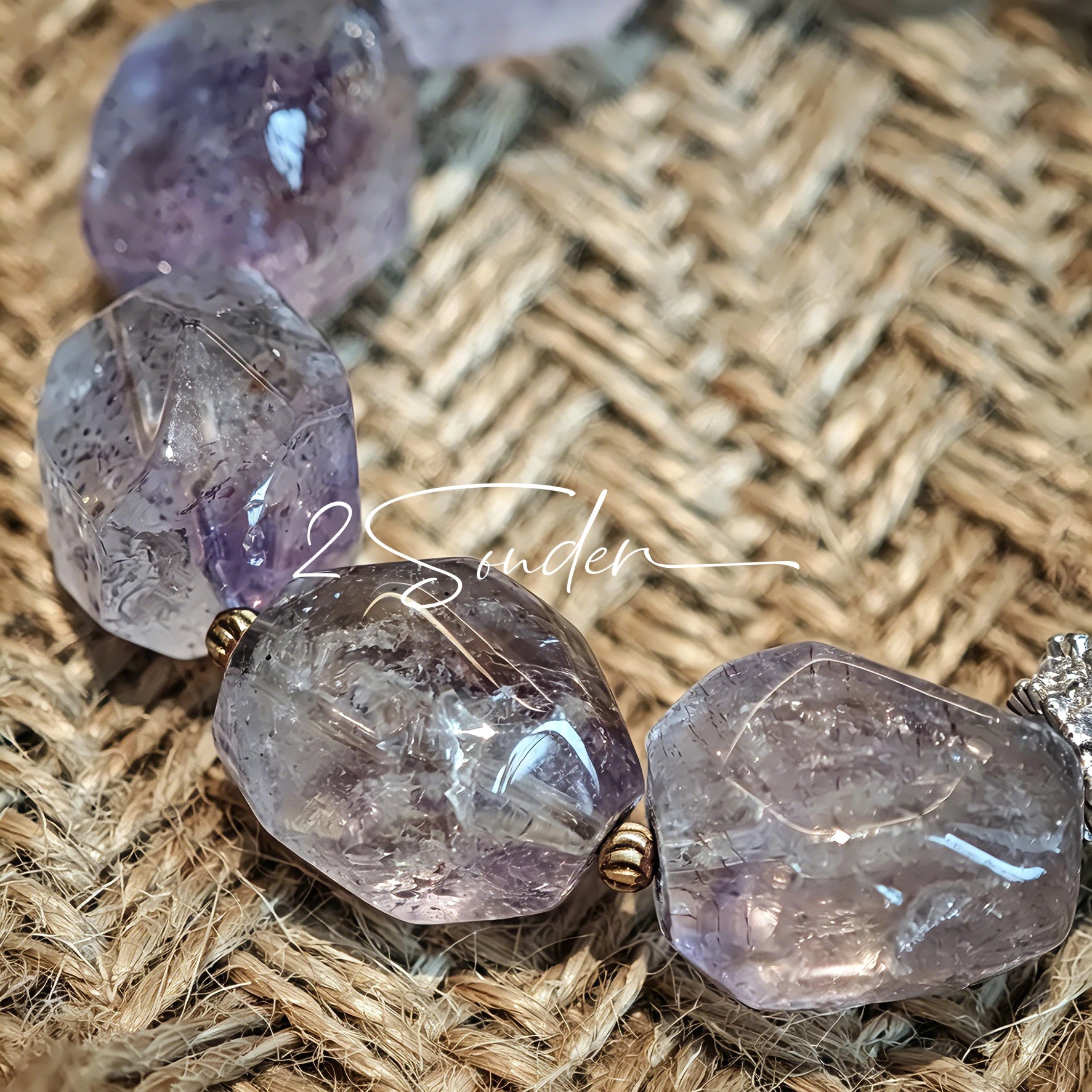 This exquisite Super Seven bracelet showcases irregularly faceted beads in a captivating blend of soft lavender and smoky purple hues, each displaying unique natural inclusions that catch the light beautifully. The polished crystals are seamlessly interspersed with tiny metallic spacer beads, culminating in an ornate silver-tone decorative bead that adds a touch of elegance to the organic design. Crafted with meticulous attention to detail, the bracelet offers a harmonious blend of rare gemstone texture and