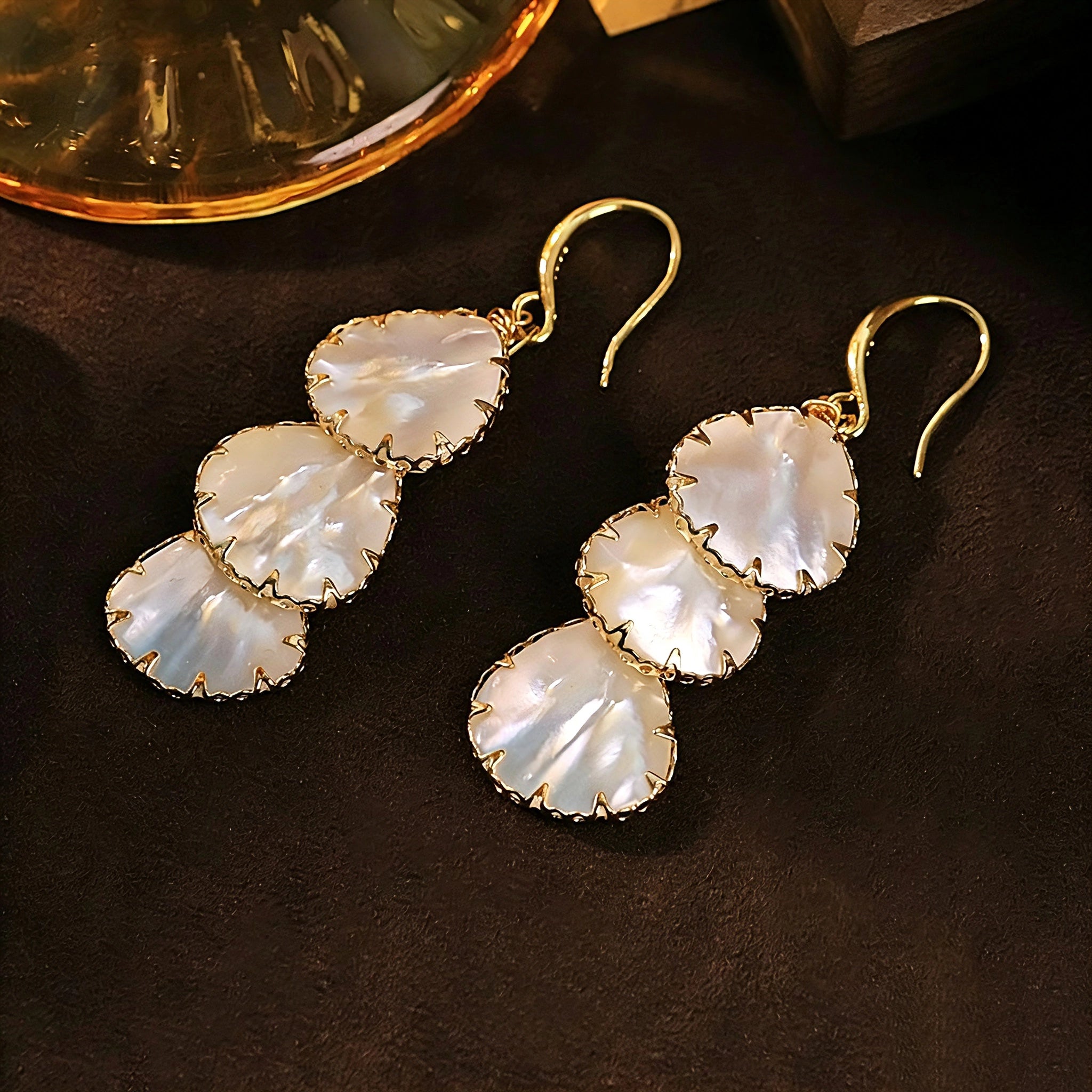 These drop earrings feature three layered natural shell slices with iridescent pearlescent luster. Each shell piece is framed by delicate gold‑tone metal trim for a vintage elegant look. The hook design offers comfortable wear for everyday and special occasions.