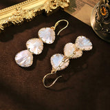 These drop earrings feature three layered natural shell slices with iridescent pearlescent luster. Each shell piece is framed by delicate gold‑tone metal trim for a vintage elegant look. The hook design offers comfortable wear for everyday and special occasions.
