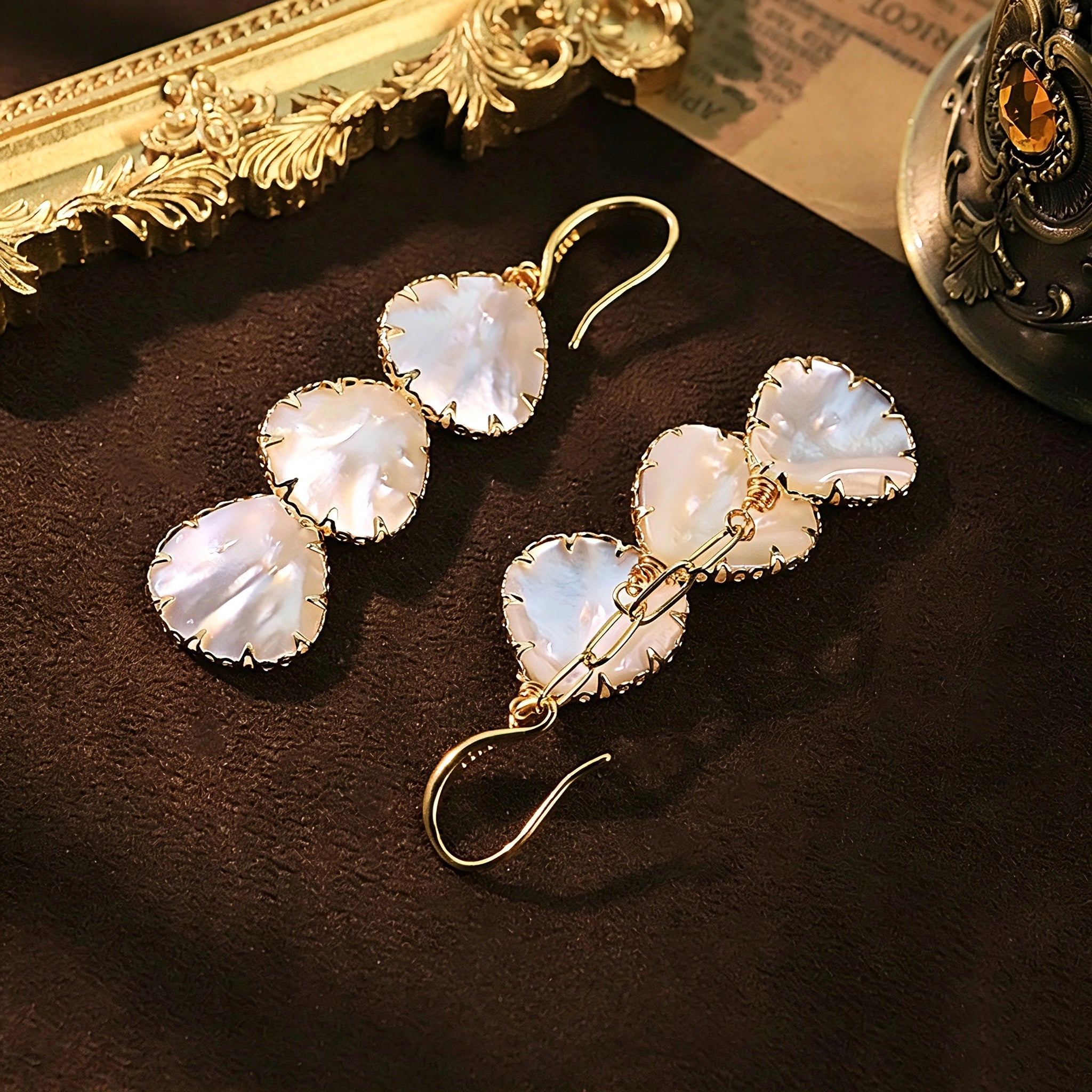 These drop earrings feature three layered natural shell slices with iridescent pearlescent luster. Each shell piece is framed by delicate gold‑tone metal trim for a vintage elegant look. The hook design offers comfortable wear for everyday and special occasions.
