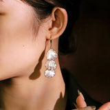 These drop earrings feature three layered natural shell slices with iridescent pearlescent luster. Each shell piece is framed by delicate gold‑tone metal trim for a vintage elegant look. The hook design offers comfortable wear for everyday and special occasions.