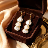 These drop earrings feature three layered natural shell slices with iridescent pearlescent luster. Each shell piece is framed by delicate gold‑tone metal trim for a vintage elegant look. The hook design offers comfortable wear for everyday and special occasions.