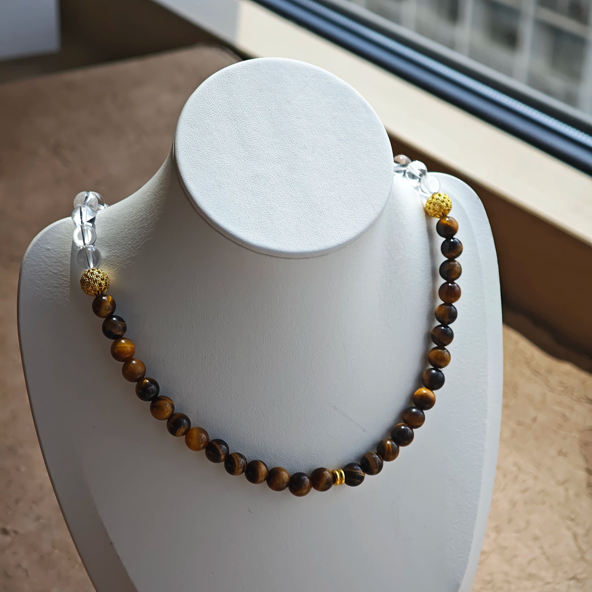 This is a necklace with tiger's eye, clear quartz, gold-plated spacer and elastic cord.