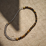 This is a necklace with tiger's eye, clear quartz, gold-plated spacer and elastic cord.