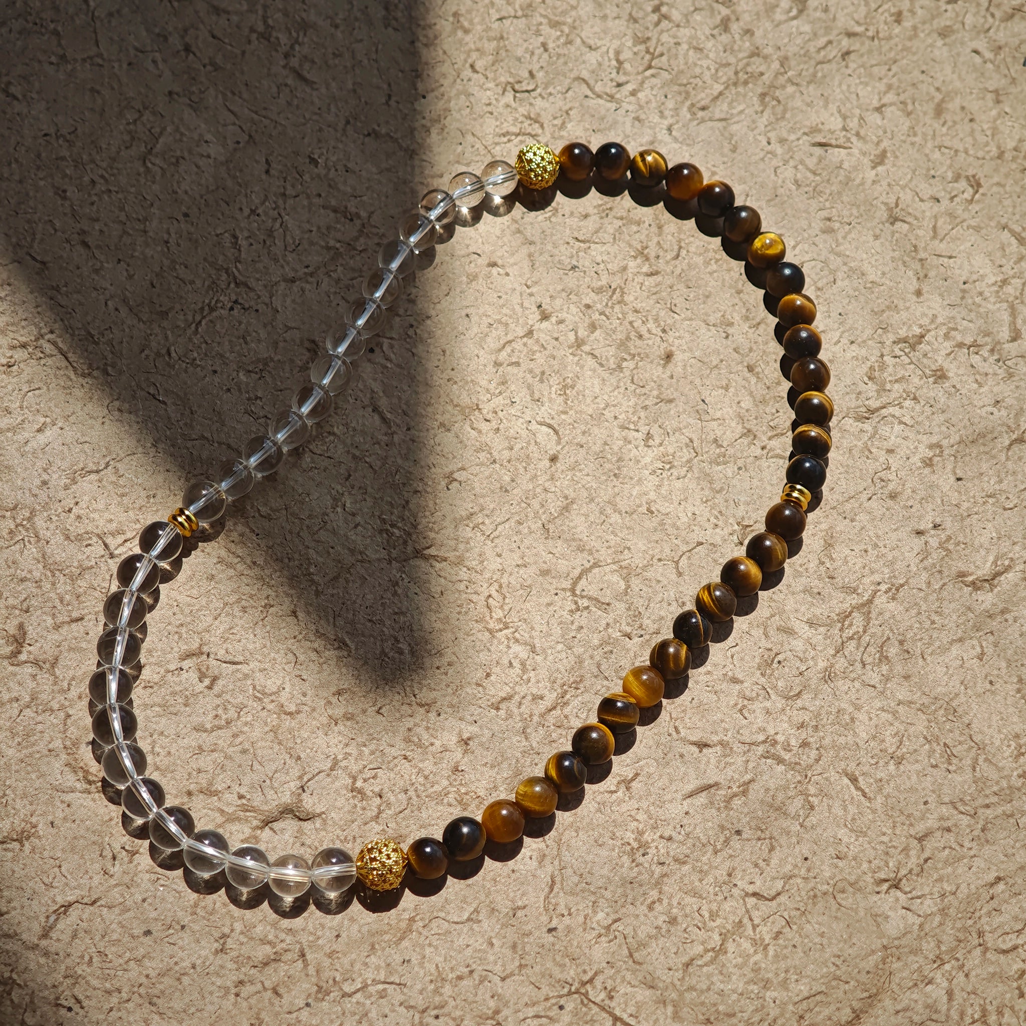 This is a necklace with tiger's eye, clear quartz, gold-plated spacer and elastic cord.