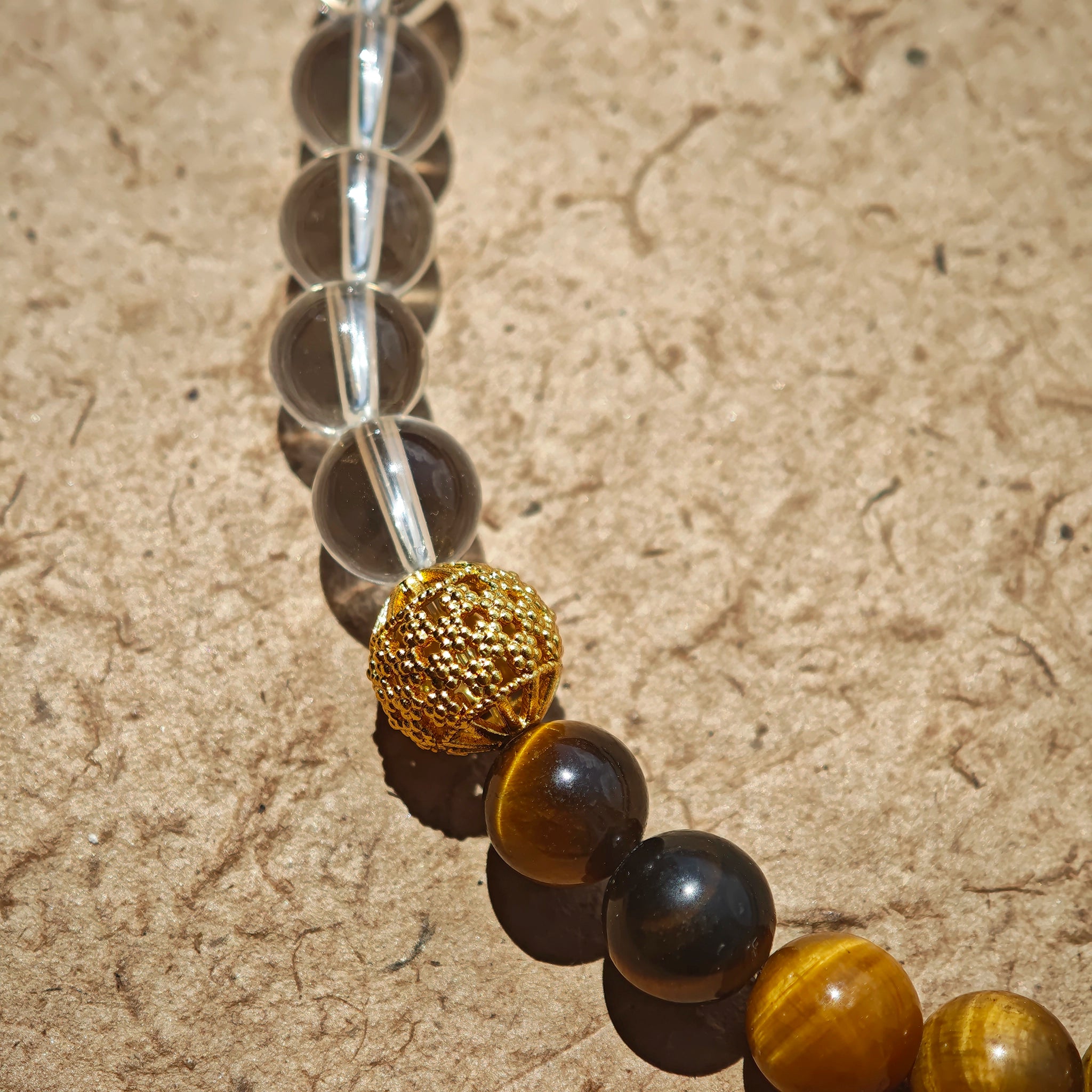 This is a necklace with tiger's eye, clear quartz, gold-plated spacer and elastic cord.