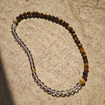 This is a necklace with tiger's eye, clear quartz, gold-plated spacer and elastic cord.