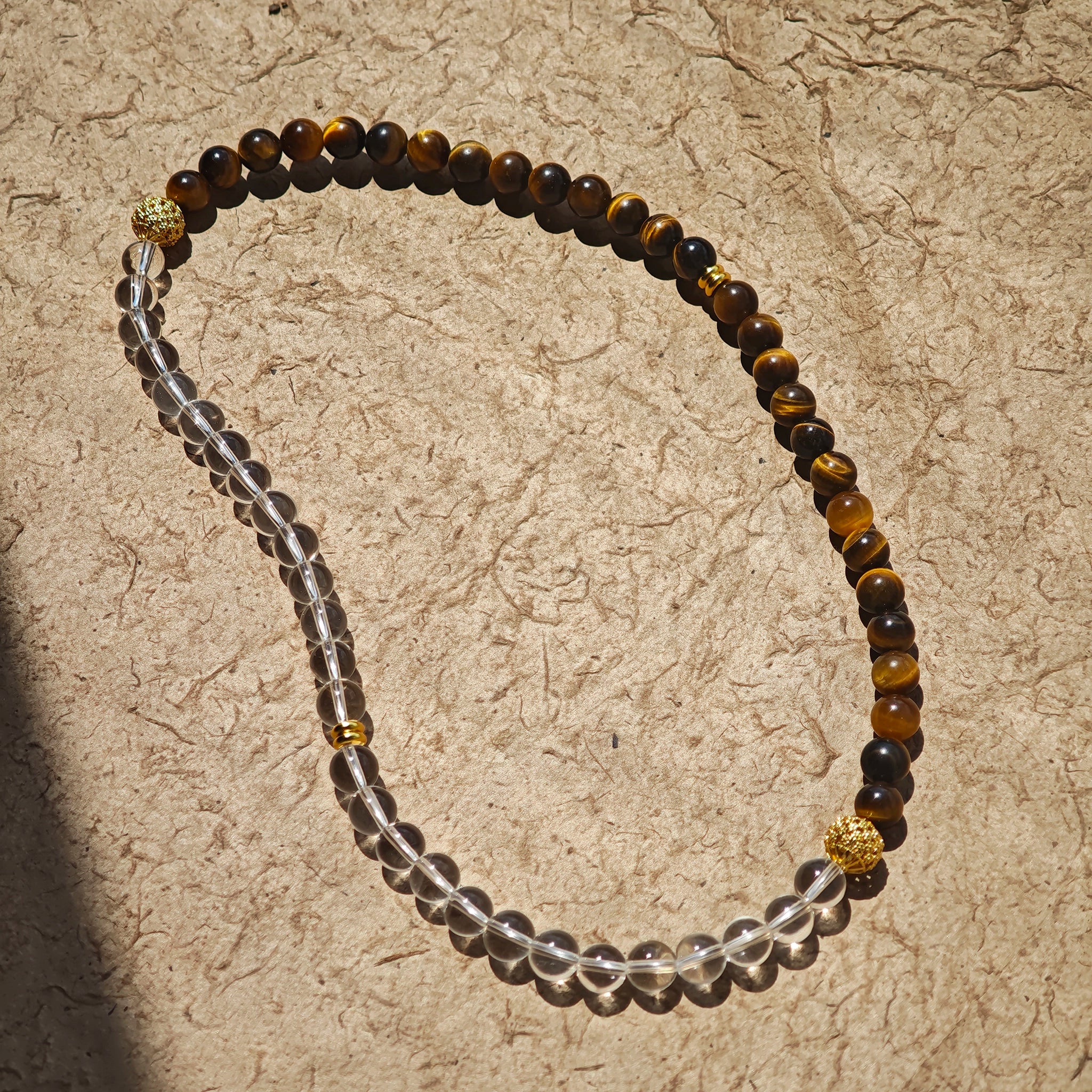 This is a necklace with tiger's eye, clear quartz, gold-plated spacer and elastic cord.