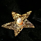 These vintage-style brooches come in star and Saturn-inspired planet shapes, with a hammered, textured finish in gold or silver tone. Each design is accented with a central gemstone, including pearl, red agate, or black onyx, adding a touch of celestial charm to any outfit.