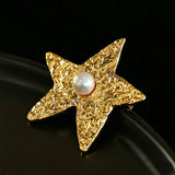 These vintage-style brooches come in star and Saturn-inspired planet shapes, with a hammered, textured finish in gold or silver tone. Each design is accented with a central gemstone, including pearl, red agate, or black onyx, adding a touch of celestial charm to any outfit.