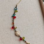 This vibrant bracelet features a colorful mix of ruby-red lemon, sapphire-blue flower, and emerald-green leaf charms, all dangling from a shimmering Czech glass bead chain.