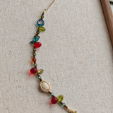 This vibrant bracelet features a colorful mix of ruby-red lemon, sapphire-blue flower, and emerald-green leaf charms, all dangling from a shimmering Czech glass bead chain.