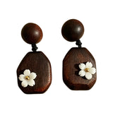 Crafted from vintage‑style dark wood, these drop earrings feature delicate small white flower accents with golden centers. Natural wood grain brings warm retro texture, suspended by black knotted cord for a soft boho‑charm look. They are lightweight statement pieces perfect for daily and casual styling.