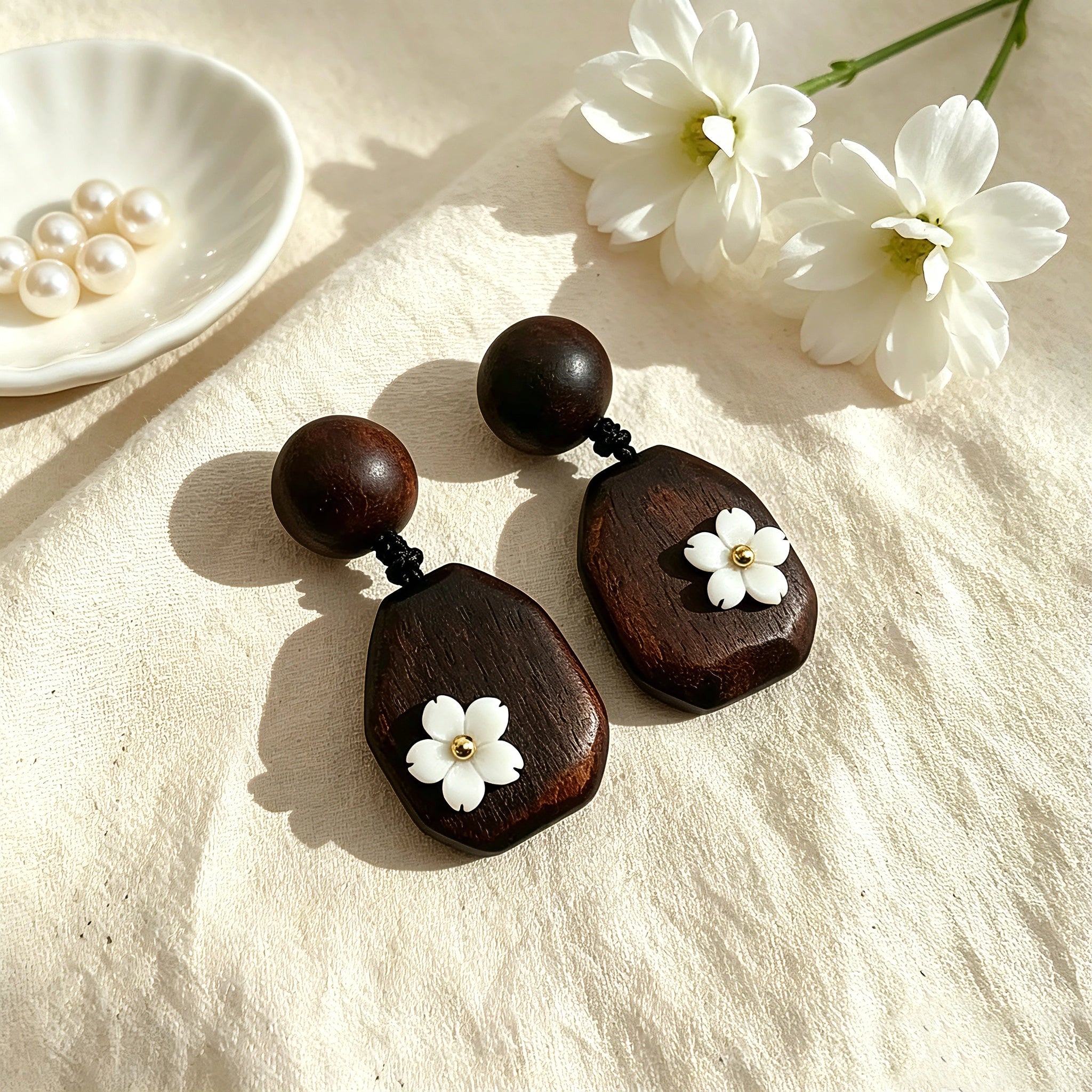 Crafted from vintage‑style dark wood, these drop earrings feature delicate small white flower accents with golden centers. Natural wood grain brings warm retro texture, suspended by black knotted cord for a soft boho‑charm look. They are lightweight statement pieces perfect for daily and casual styling.
