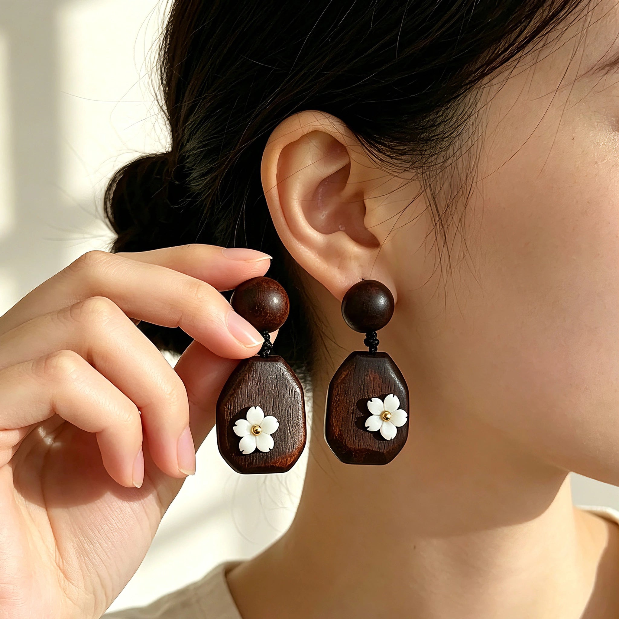 Crafted from vintage‑style dark wood, these drop earrings feature delicate small white flower accents with golden centers. Natural wood grain brings warm retro texture, suspended by black knotted cord for a soft boho‑charm look. They are lightweight statement pieces perfect for daily and casual styling.