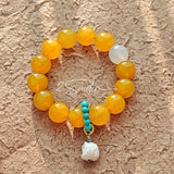 This handcrafted bracelet features glossy 14mm yellow agate beads paired with one white agate bead. It is accented with turquoise beads and finished with a detailed mammoth ivory guardian lion charm, bringing a warm vintage ethnic vibe.