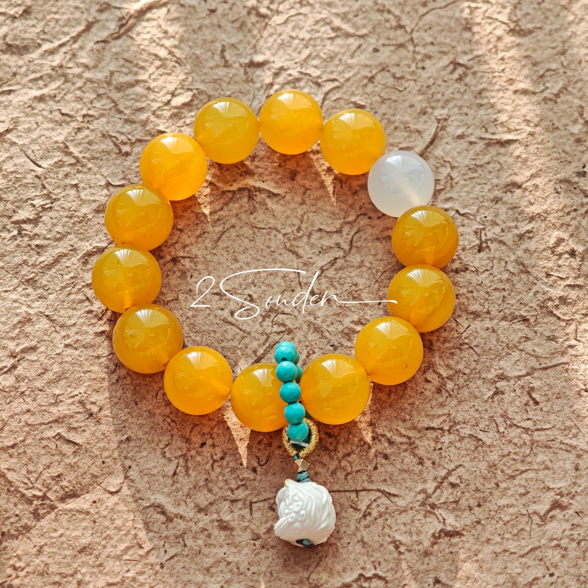 This handcrafted bracelet features glossy 14mm yellow agate beads paired with one white agate bead. It is accented with turquoise beads and finished with a detailed mammoth ivory guardian lion charm, bringing a warm vintage ethnic vibe.