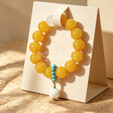 This handcrafted bracelet features glossy 14mm yellow agate beads paired with one white agate bead. It is accented with turquoise beads and finished with a detailed mammoth ivory guardian lion charm, bringing a warm vintage ethnic vibe.