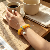This handcrafted bracelet features glossy 14mm yellow agate beads paired with one white agate bead. It is accented with turquoise beads and finished with a detailed mammoth ivory guardian lion charm, bringing a warm vintage ethnic vibe.
