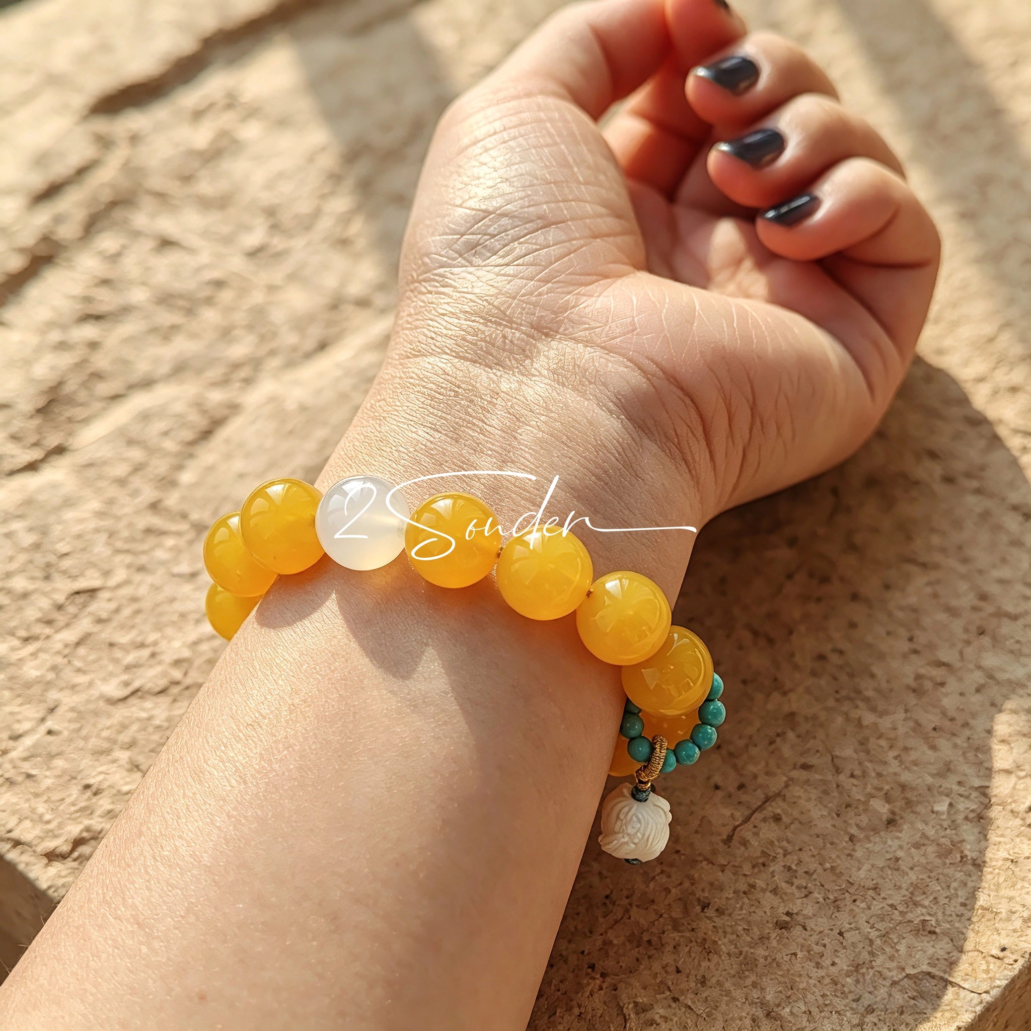 This handcrafted bracelet features glossy 14mm yellow agate beads paired with one white agate bead. It is accented with turquoise beads and finished with a detailed mammoth ivory guardian lion charm, bringing a warm vintage ethnic vibe.