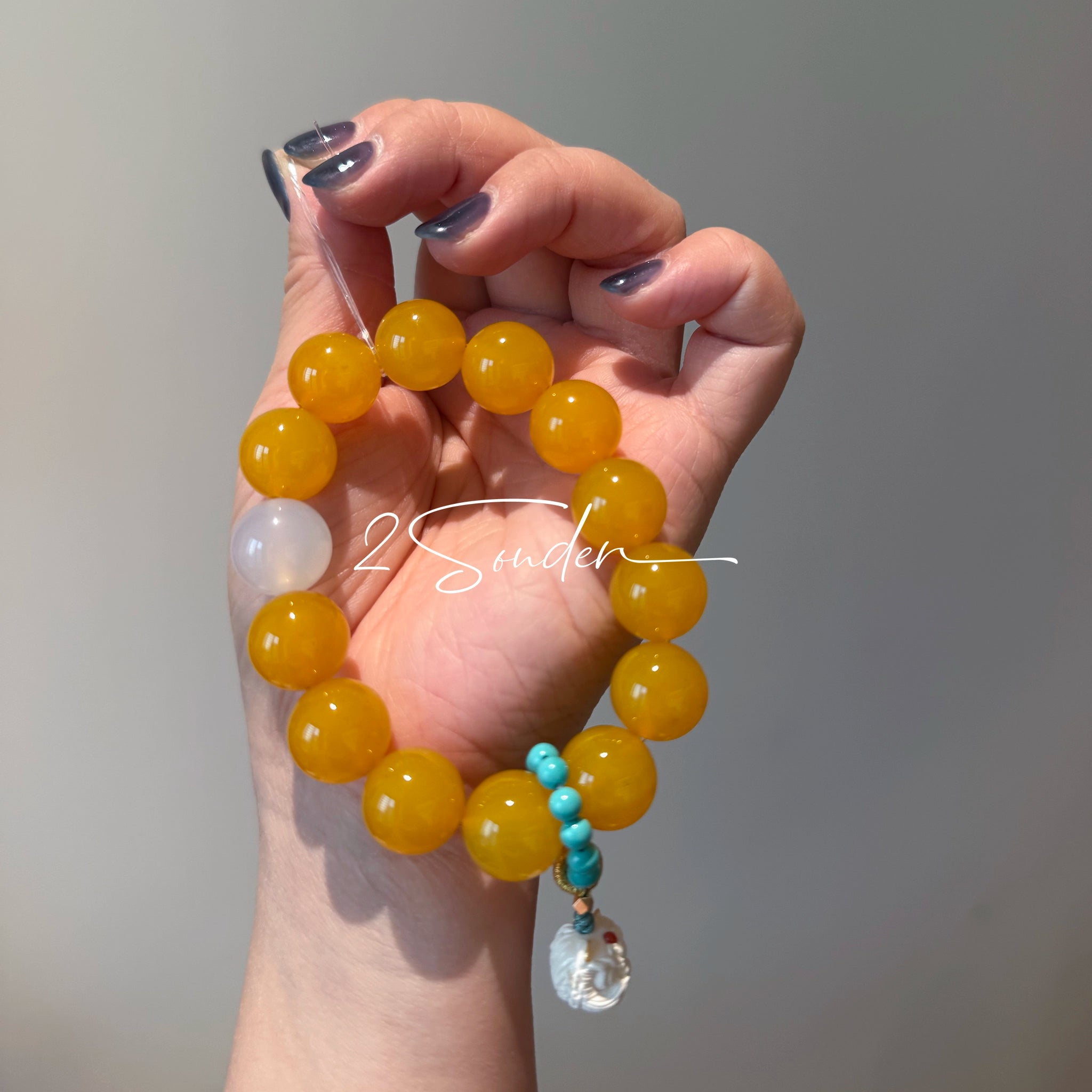 This handcrafted bracelet features glossy 14mm yellow agate beads paired with one white agate bead. It is accented with turquoise beads and finished with a detailed mammoth ivory guardian lion charm, bringing a warm vintage ethnic vibe.